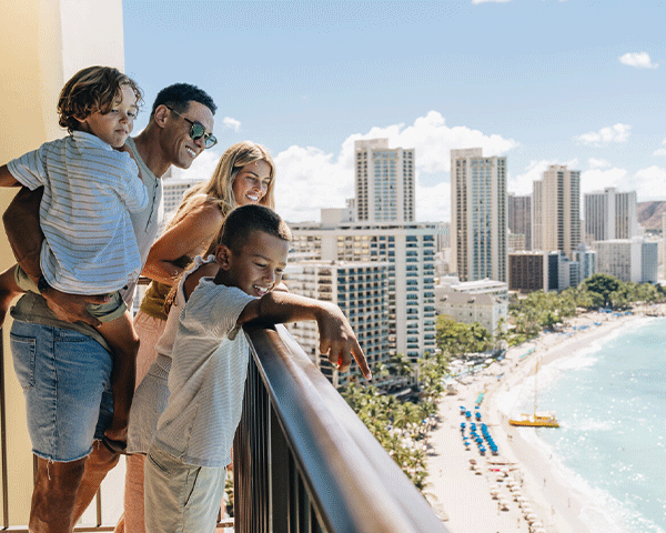 Family enjoying the balcony view at their Hawaii hotel room.