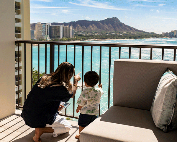 Mother and son looking out their balcony in their Hawaii hotel room.