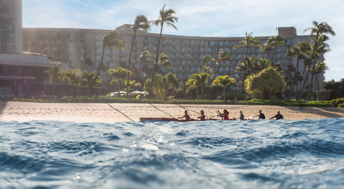 Men are rowing their boat by the beach.
