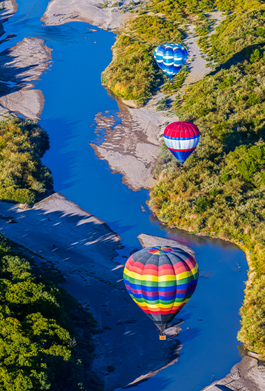 Aerial view of colorful hot-air balloons floating over the Rio Grande Valley.