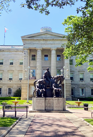 Sunny photo of a statue in front of a building.