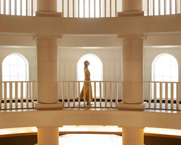 Woman walking through a hallway with beautiful architecture.