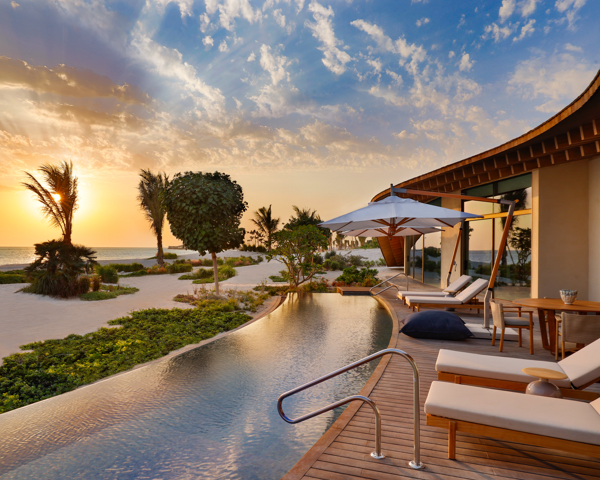 Infinity pool deck overlooks lush, tropical view at golden hour.