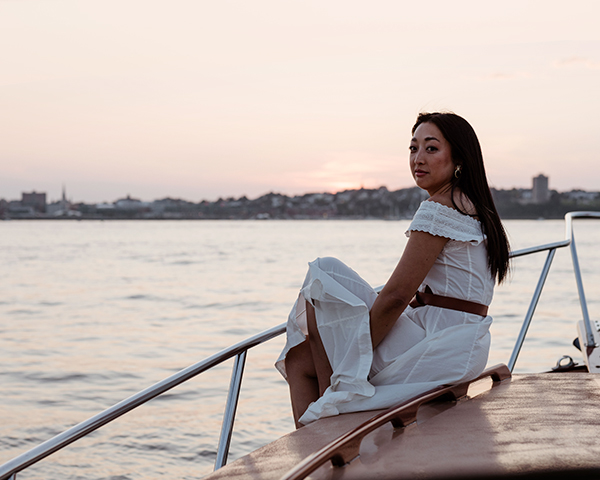 Woman wearing a white dress enjoying a sunset boat tour.