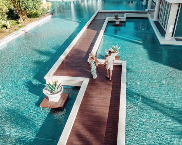 Couple walking along an infinity pool at a Marriott Bonvoy property.