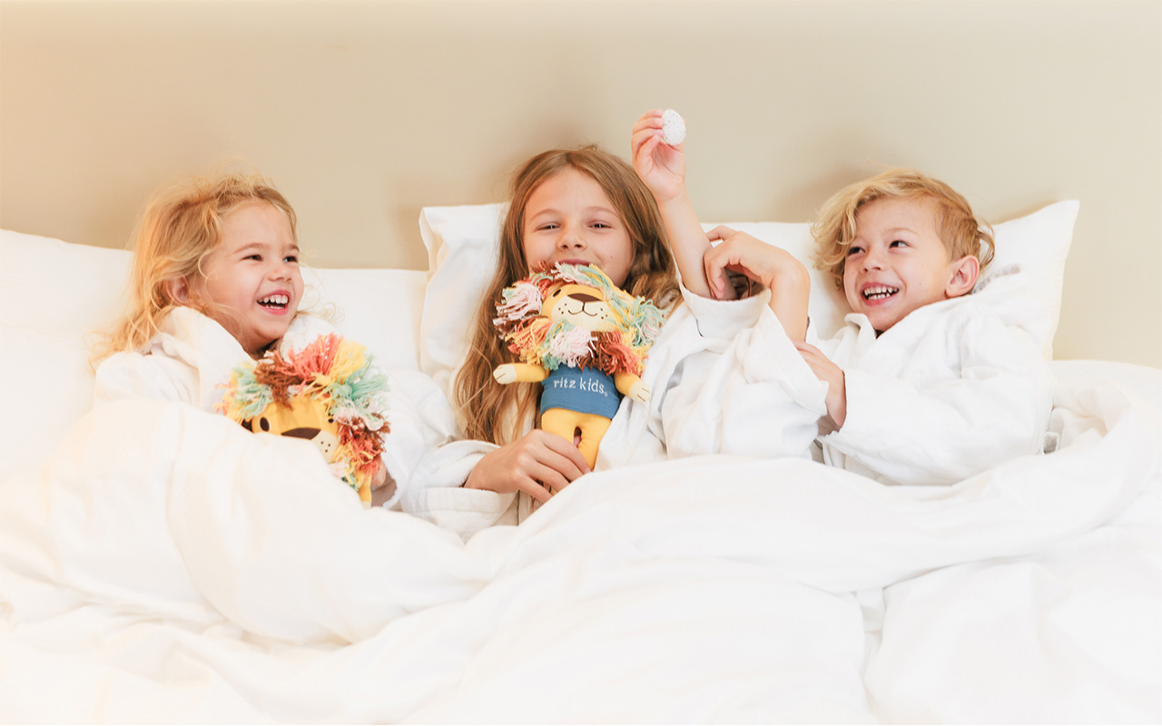 Various fragrances from Westin's White Tea Collection displayed on a gray table and against a wooden wall background. Soft lighting is shining on the products.