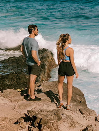 Young couple on a rocky shoreline overlooking the ocean.