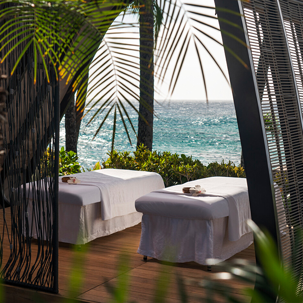 Two message tables under a canopy of palm trees, the ocean in the background