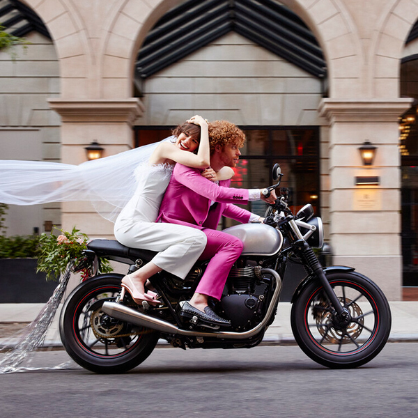 A young bride and groom riding a motorcycle