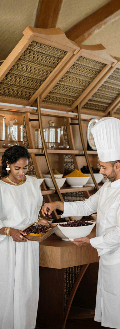 A woman learning how to prepare a meal with a trained chef at Nujuma, a Ritz-Carlton Reserve.