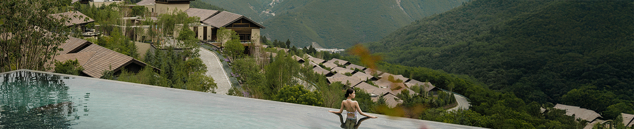 Woman in a rooftop pool overlooking Rissai Valley, China.