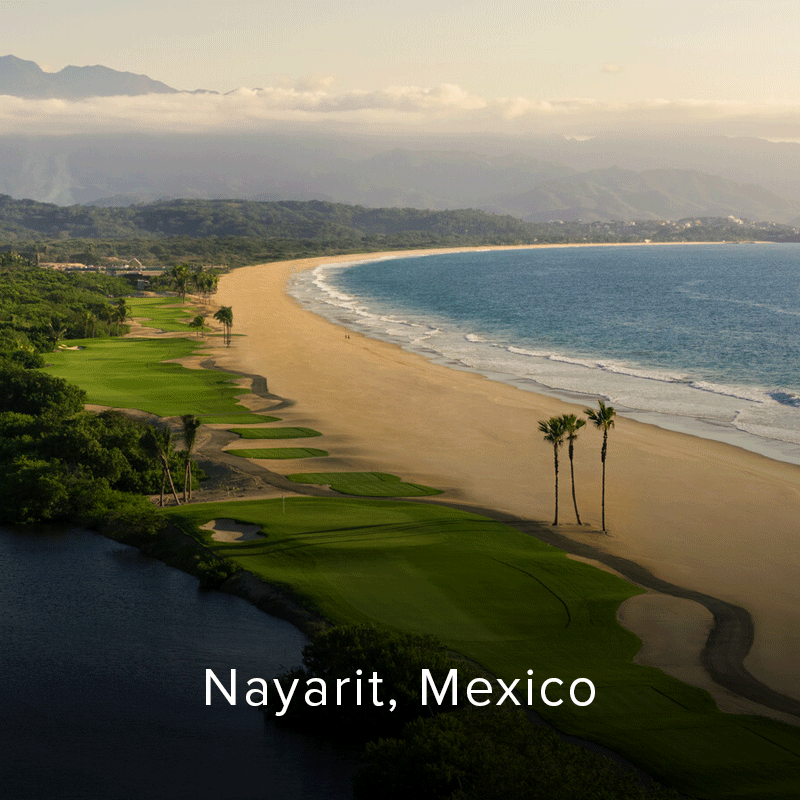Coastal view of a tropical golf course beside a sandy beach and blue ocean.